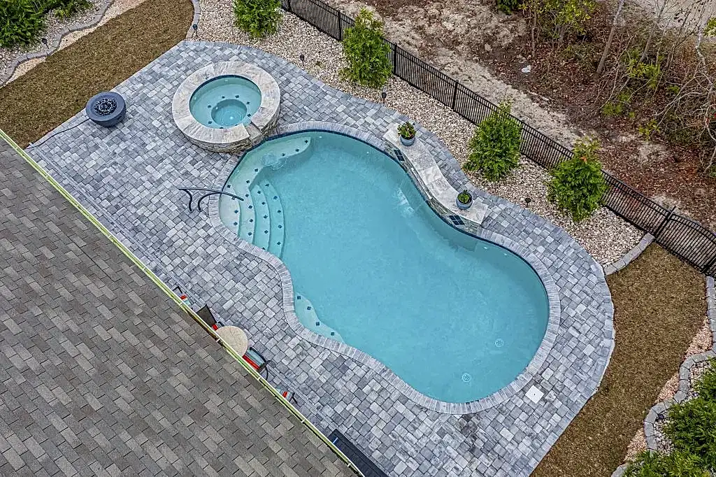 Lux Project 14 custom oasis pool with integrated spa, surrounded by waterfalls and a fireplace