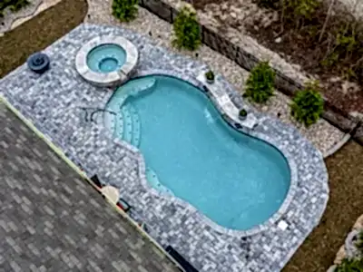 Lux Project 14 custom oasis pool with integrated spa, surrounded by waterfalls and a fireplace